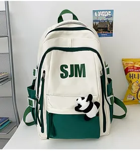 Detalle de una mochila vintage blanca y verde para estudiantes con peluche de panda