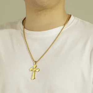 Detailed view of a gold-plated baseball cross necklace worn on a plain white T-shirt.