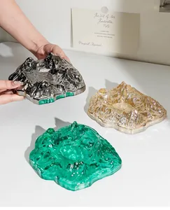 Detailed view of luxury mountain-shaped glass ashtrays in silver, amber, and green.