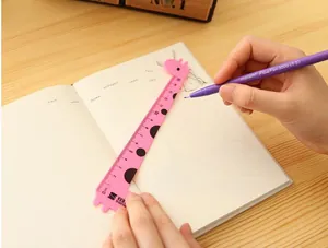Vista detallada de una regla de plástico rosa con forma de jirafa en un cuaderno de papel