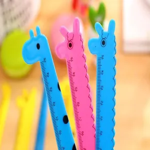 Primer plano de simpáticas reglas de plástico con forma de jirafa y escala de 15 cm