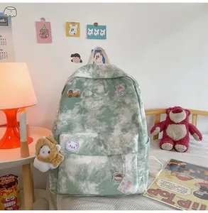 Macro view of green tie-dye backpack featuring cute cartoon patches and plush charm