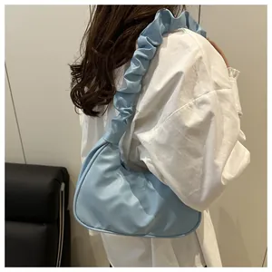 Dettaglio di una borsa sottobraccio arricciata celeste indossata con camicia bianca