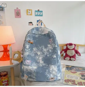 Detail of blue tie-dye backpack showing cute cartoon pins and plush doll accessories