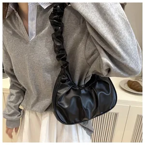 Vista dettagliata della borsa hobo a pieghe nera indossata a spalla da una modella.