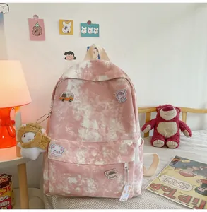 Detail view of cute pink tie-dye student backpack with cartoon patches and plush charm