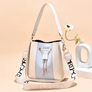 Elegant cream and blue bucket bag with decorative gold chains and wide strap