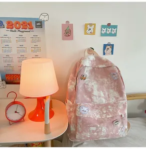Close-up of pink tie-dye backpack with cute decorative patches in a cozy room setting