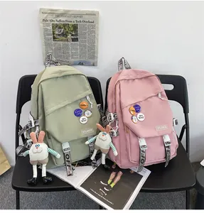 Two stylish student backpacks in green and pink with cute badges and plush charms