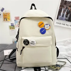 Vue détaillée d'un sac à dos en toile blanche minimaliste avec badges décoratifs