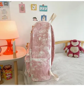 Detailed side view of a cute pink and white tie-dye printed backpack in a cozy room setting