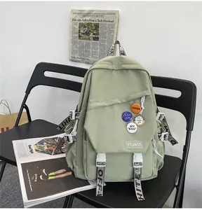 Detailed view of a light green student backpack with decorative pins placed on a black chair