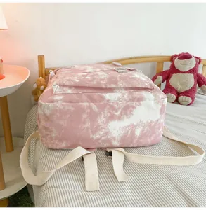 Pink and white tie-dye student backpack resting on a striped bed in a bedroom
