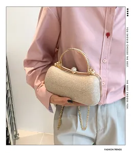 Detailed view of champagne gold evening clutch with rhinestone handle and chain strap