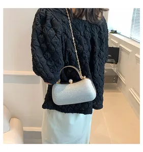 Elegant silver glitter evening clutch bag with gold chain strap worn by a woman.