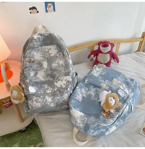 Detailed view of blue and gray tie-dye backpacks with cute character plush keychains
