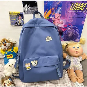 Zaino scolastico blu minimalista per studenti con graziose spille a fumetti in una stanza accogliente