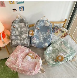 Multiple colors of tie-dye print backpacks for students with cute pins and charms