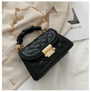 Detail of black quilted small square bag with gold chain strap and ruffled handle.