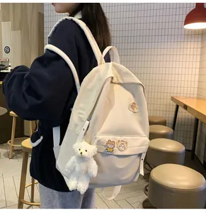 Scatto lifestyle di uno zaino in tela crema con simpatiche toppe e portachiavi a forma di orsetto