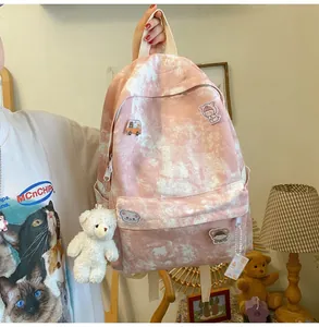 Detailed view of cute pink tie-dye student backpack with plush bear keychain accessory