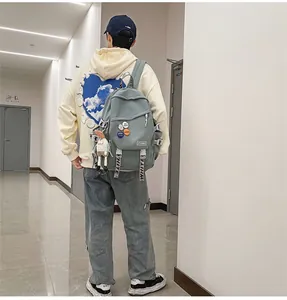 Rear view of a grey large capacity student backpack with decorative pins and charms