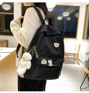 Primo piano di uno zaino nero minimalista con spille a cartone e portachiavi peluche