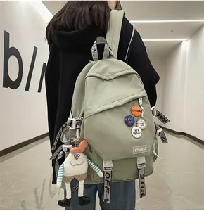 Detailed back view of a sage green large capacity backpack with cute charms and pins