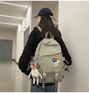 Detail view of stylish sage green backpack featuring badges and a cute rabbit charm