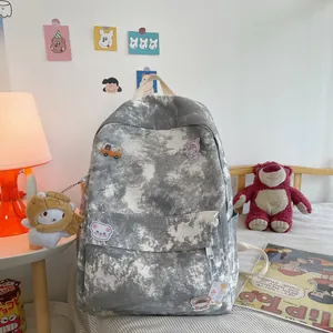 Stylish grey and white tie-dye backpack for students featuring cute plush charm and pins