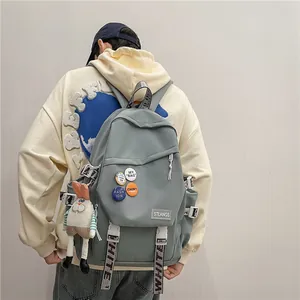 Stylish large capacity grey student backpack with decorative badges and a plush bunny