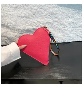 Gros plan d'un sac à main rose en forme de cœur avec une sangle LOVE colorée