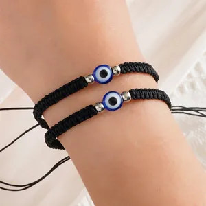 Detailed macro view of two black braided evil eye bracelets on wrist with adjustable cords