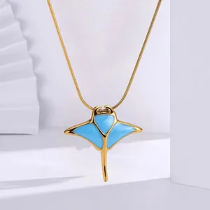 Close-up of a stylish gold stainless steel manta ray pendant with blue enamel details.