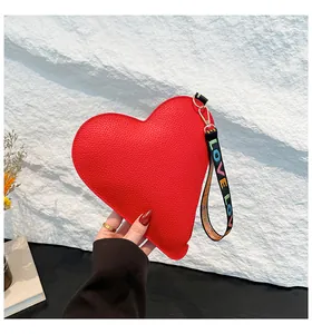 Gros plan d'un sac à main rouge en forme de cœur avec une dragonne imprimée LOVE.