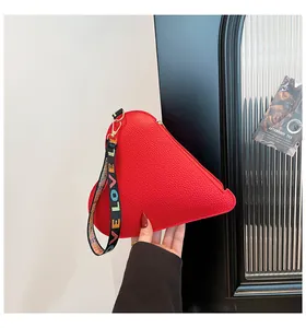 Gros plan sur un sac à main rouge en forme de cœur avec une sangle LOVE colorée