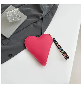 Gros plan d'un sac à main en forme de cœur avec texture grainée et sangle LOVE colorée.