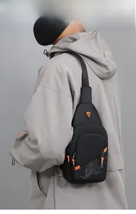 Detail view of a black men's chest bag with orange accents worn over a grey jacket.