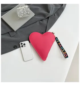 Gros plan d'un sac à main rose en forme de cœur avec une sangle colorée 'LOVE' et texture.