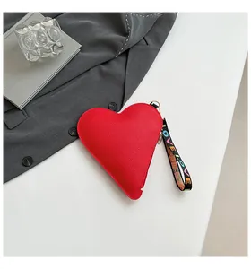 Gros plan sur un sac à main rouge en forme de cœur avec texture grainée et sangle LOVE