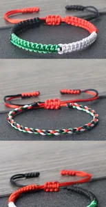 Macro detail of handmade braided cord bracelets in flag-themed red, green, and black.