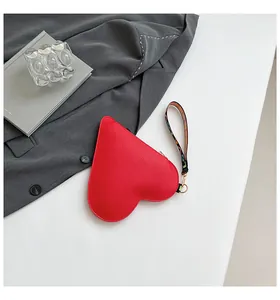 Élégante pochette rouge en forme de cœur en cuir texturé avec dragonne décorative.