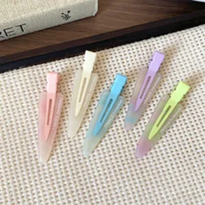 Detail view of five assorted pastel matte resin alligator hair clips on white mesh