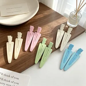 Close-up macro view of matte pastel pointed hair clips arranged on a wooden tray background