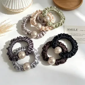 Detail shot of elegant assorted color satin scrunchies with large round white pearls.