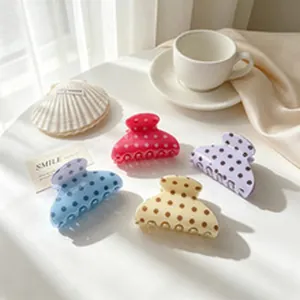 Group of colorful polka dot hair claw clips in pastel shades displayed on a white table