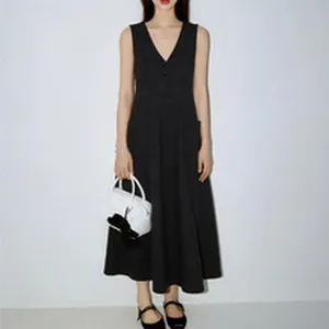 Femme portant une robe longue noire sans manches à col en V avec un sac à main blanc