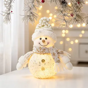 Close-up view of a glowing snowman plush ornament with warm LED light and gold scarf