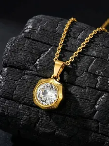 Détail macro d'un pendentif en acier doré avec zircon blanc sur charbon de bois