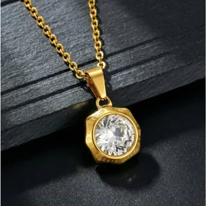 Gros plan d'un collier en acier inoxydable doré avec un pendentif en zircon blanc brillant.